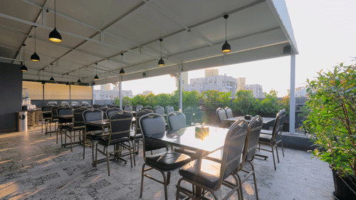 An image of a restaurant at the rooftop where many tables and chairs are placed -  Magnus Fortune House, Magarpatta