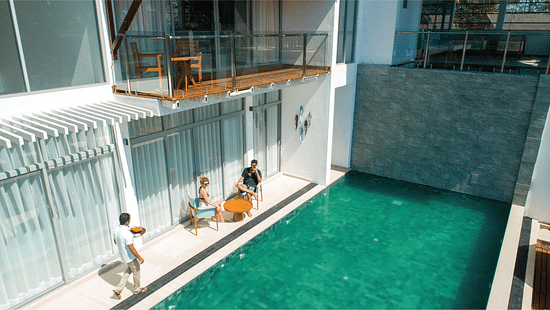 a clear greenish-blue pool at Beacon by the Bay Villas & Suites by The Clarks, Dondra featuring people chilling at the deck as the waiter is walking to them with food