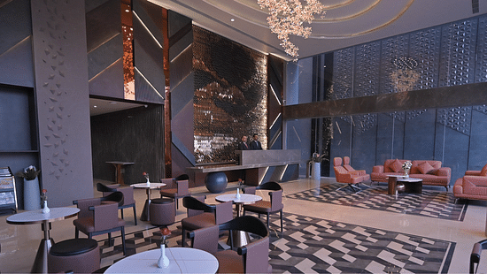 Reception and lobby at Clarks Collection Ajmer featuring a large sitting area with tables and chairs and sofa sets as two receptionists are present at the desk