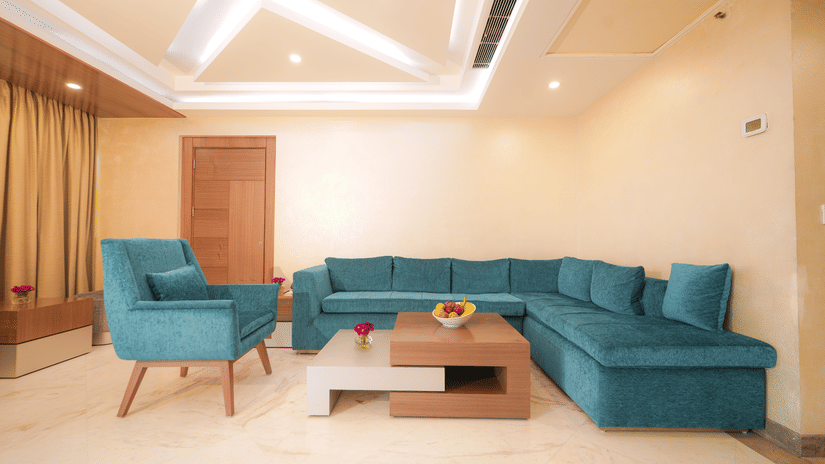 Executive Suite area at The Suryaa New Delhi featuring a blue aligned sofa and a table placed at the centre