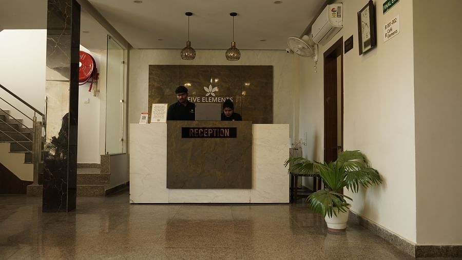 Reception at Five Elements Hotels, Haridwar, featuring a flower pot in the corner and a staircase on the other side