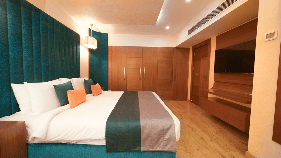 Executive Suite bedroom at The Suryaa New Delhi featuring a spacious wardrobe and a dedicated television unit