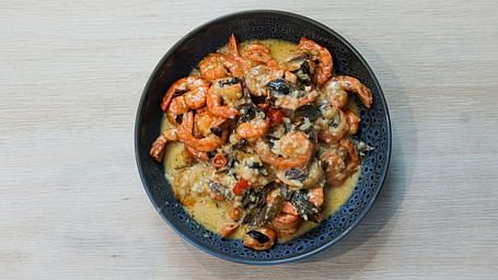An aerial view of a prawn curry in a bowl kept on a table.