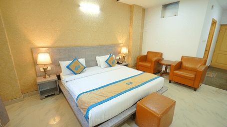 A side angle shot o the king size bed in the room along with two couches | DLS Hotel Shiva Sanctuary & Spa, Dharamshala