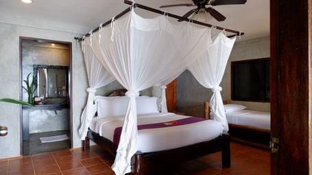 Elegant villa interior with twin canopy beds and polished wooden floors at Flower Island Resort.