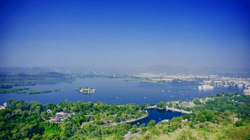 Aerial view of a lake surrounded by hills on a clear, blue day