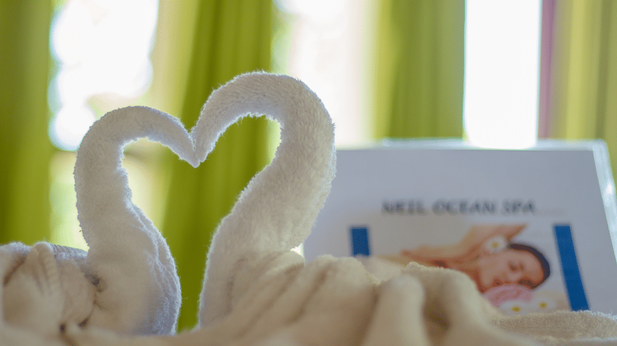 Towels in a shape of birds making a heart shape placed on the massage table - Symphony Summer Sand Beach Resort And Spa, Neil Island