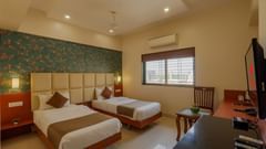 twin bed in a deluxe room with bright and vibrant colours with room amenities like television and air-conditioning - Magnus Square, Viman Nagar