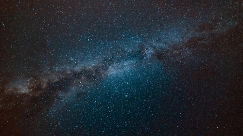 A space night-sky view of the bright band of the Milky Way galaxy against a dark expanse.