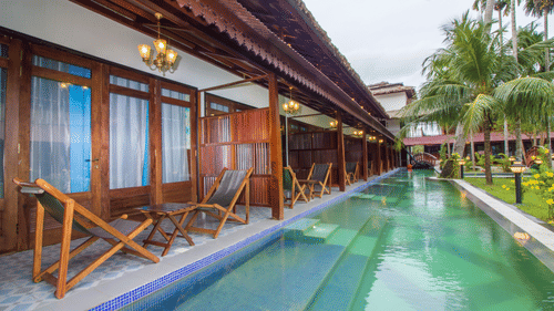 A swimming pool in from of Casa Aqua with chairs on the balcony at Symphony Summer Sand Beach Resort And Spa, Neil Island.
