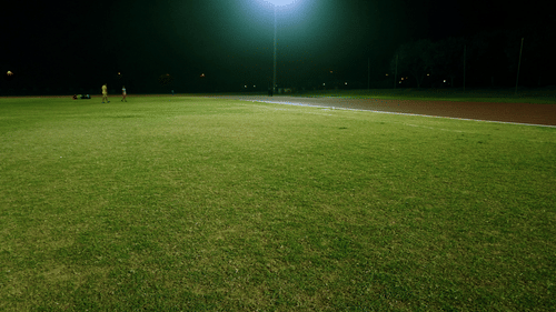 A large and empty lawn illuminated by a lampost during the night.