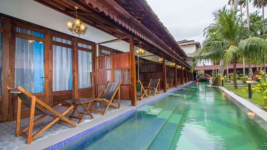 a swimming pool in from of Casa Aqua with chairs on the balcony - Symphony Summer Sand Beach Resort And Spa, Neil Island