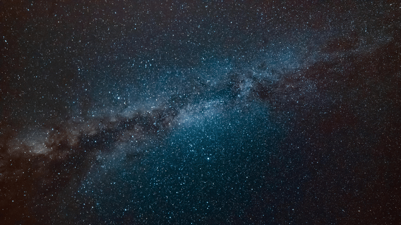 A space night-sky view of the bright band of the Milky Way galaxy against a dark expanse.