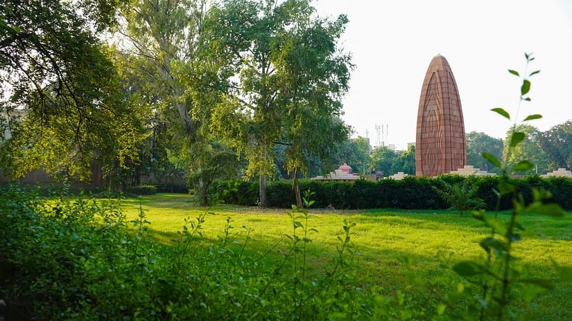 A tranquil green landscape with lush trees, leading to a distant historical monument
