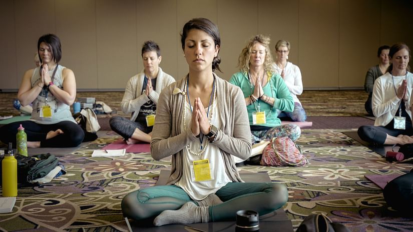 a group of women practicing Yoga by sitting and folding hands and meditating