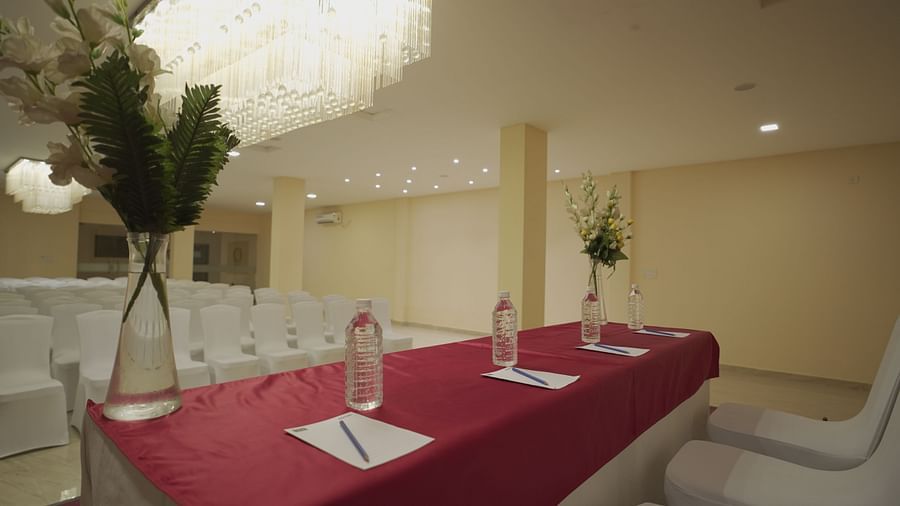 Apollo Banquet Hall at Citrus Classic Resorts and Spa Mahabalipuram ECR featuring a table on the stage with pen and paper, water bottles and vases