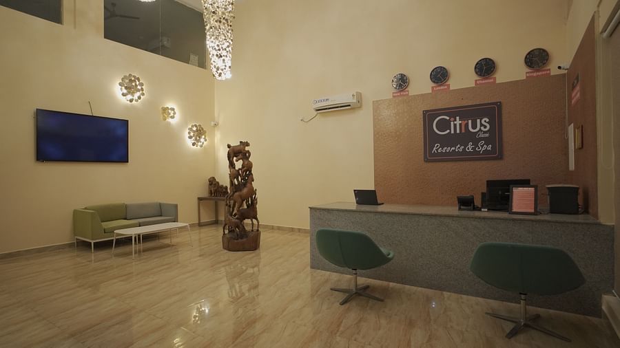 The reception area of Citrus Classic Resorts & Spa features a sleek desk, decorative wall clocks, wooden horse sculpture, and cosy seating at Citrus Classic Resorts and Spa Mahabalipuram ECR