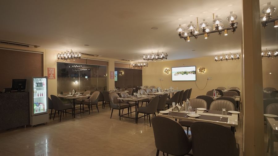 A chic restaurant featuring marble tables, grey chairs, and elegant chandeliers. Soft lighting and large windows create a cosy vibe at Citrus Classic Resorts and Spa Mahabalipuram ECR