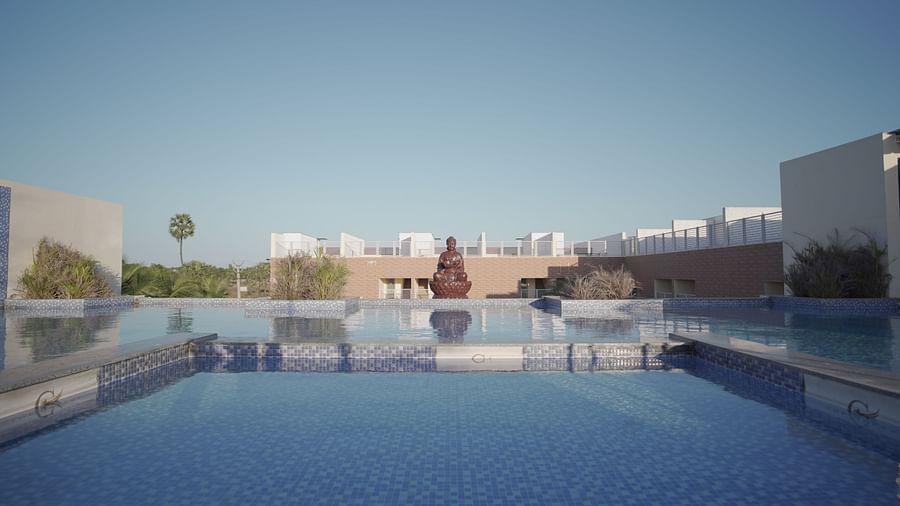 A large swimming pool at Citrus Classic Resorts and Spa Mahabalipuram ECR reflecting the surroundings on the water on a sunny day