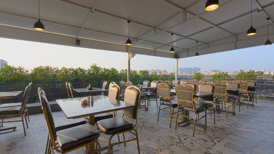 An image of a restaurant at the rooftop where many tables and chairs are placed -  Magnus Fortune House, Magarpatta