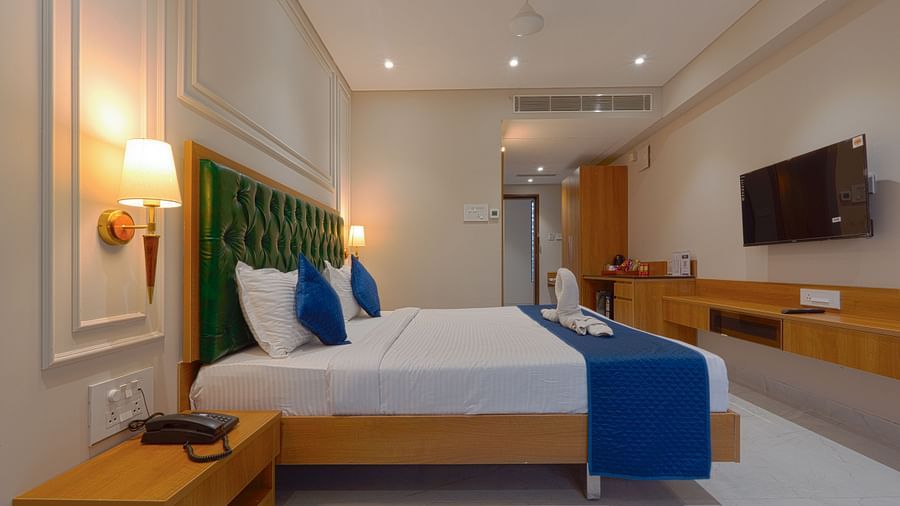 A double bed with side tables and lamps inside deluxe suites - Magnus Nexstar Suites, Pune