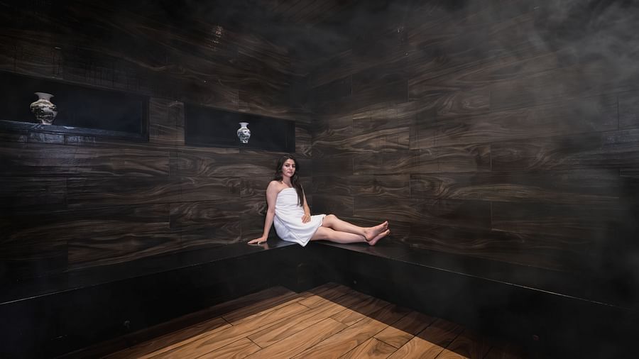 An image of a woman sitting in a counter top of a Sauna Room - The Manor Luxury Hotel, Shimla