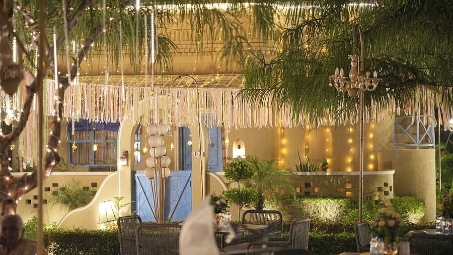 An outdoor seating arrangement adorned with lights and drapes at Themis Mudhouse – A Nature Retreat Resort & Wellness.