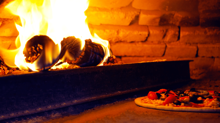 A wood-fired oven burning with bright flames inside a traditional kitchen - Ramada by Wyndham Addis