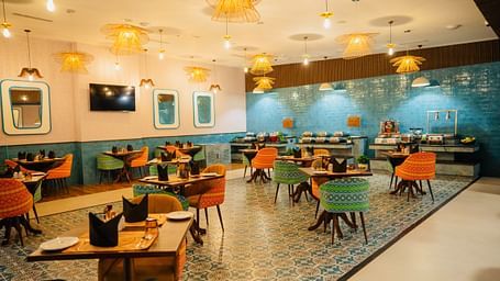 A dining area with chic hanging lights illuminating the table at Zibe Luxe Kakinada by GRT Hotels