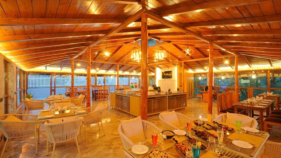 An image of a restaurant with bright yellow lighting and seating arrangement - DLS The Emerald, Nainital