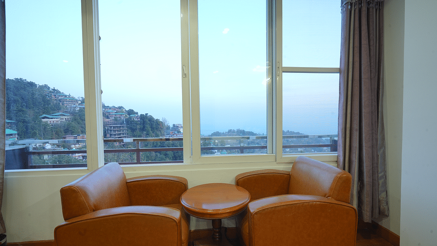 A cosy seating area with two armchairs and a small table in front of a large window | DLS Hotel Shiva Sanctuary & Spa, Dharamshala
