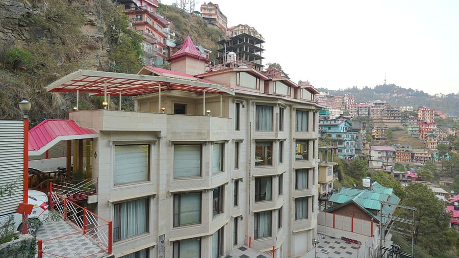 Side view of the  DLS Hotels The Rock Castle, Shimla exterior with multiple buildings in the background.