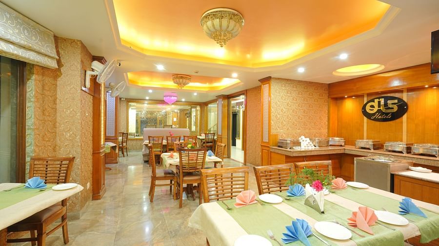 Dining area with a table and chairs, featuring the DLS logo on the wall and yellow ceiling lights illuminating the space at DLS Hotels The Rock Castle.