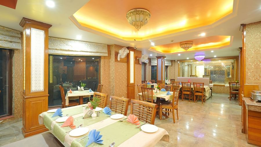Dining area with a table set with cutlery, chairs, and soft yellow lighting from the ceiling at DLS Hotels The Rock Castle.