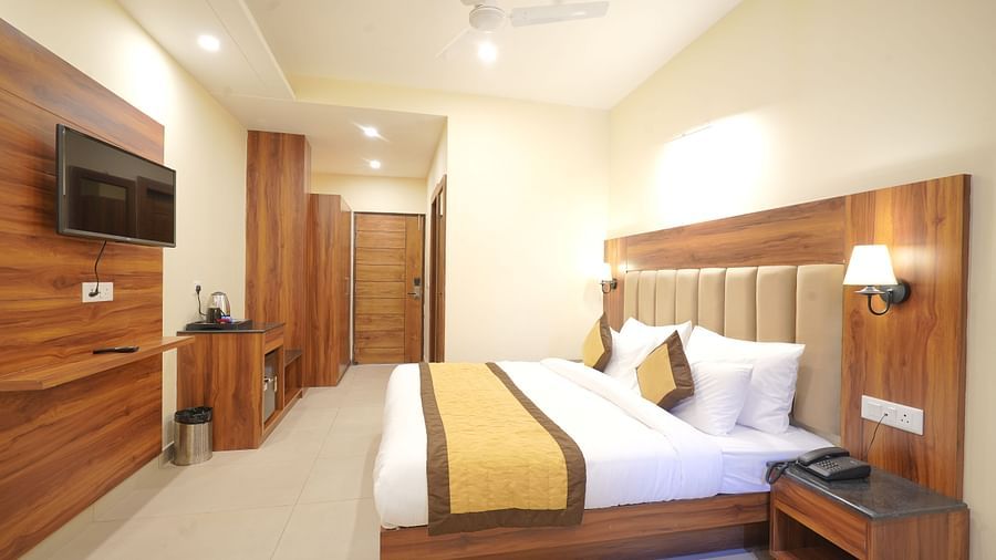 A large bed in front of the TV near a nightstand Deluxe Room at DLS Oak Bush, Musssoorie.