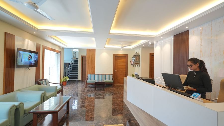 Reception area with a receptionist standing near the desk at DLS Oak Bush, Mussoorie.