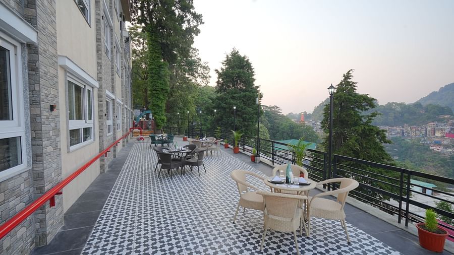 An outside seating area with comfortable chairs around tables at DLS Oak Bush, Mussoorie.