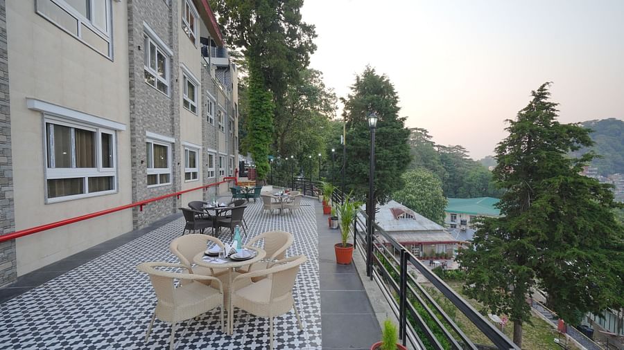 An outside seating area with comfortable chairs around tables at DLS Oak Bush, Mussoorie.