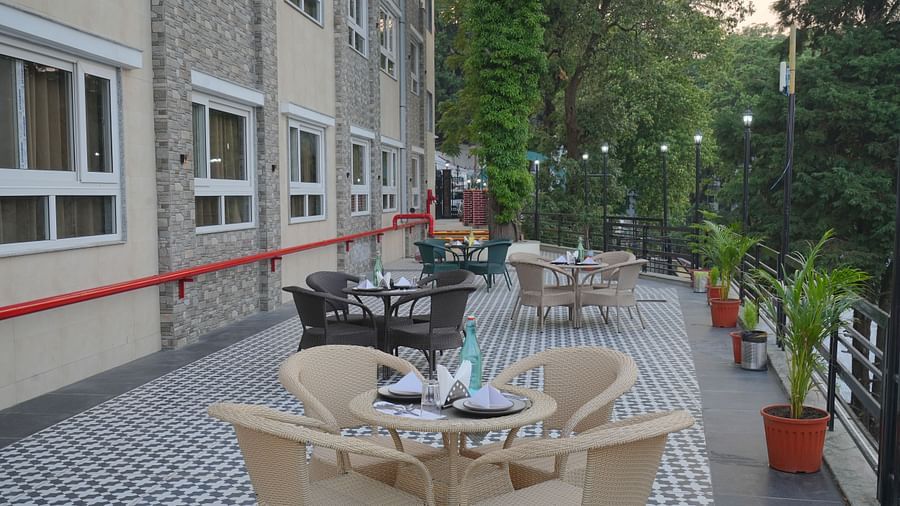 An outside seating area with comfortable chairs around tables at DLS Oak Bush, Mussoorie.