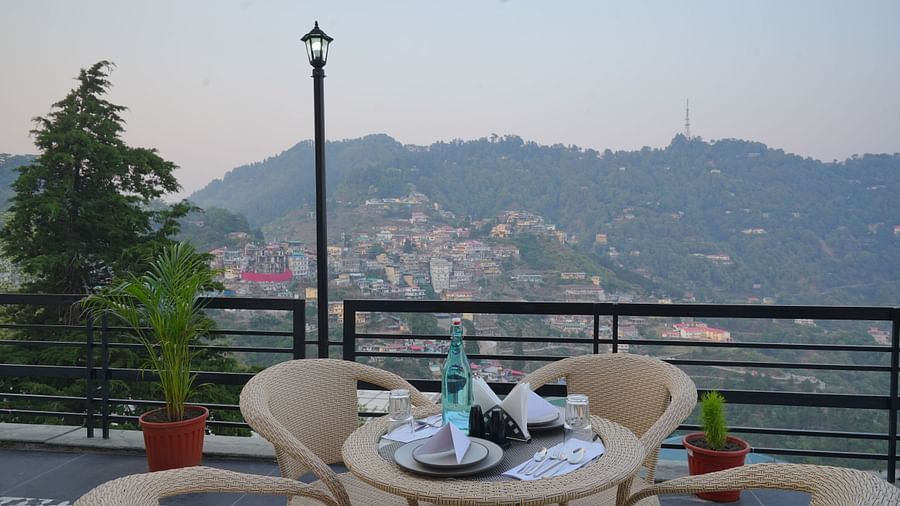 An outside seating area with comfortable chairs around tables at DLS Oak Bush, Mussoorie.