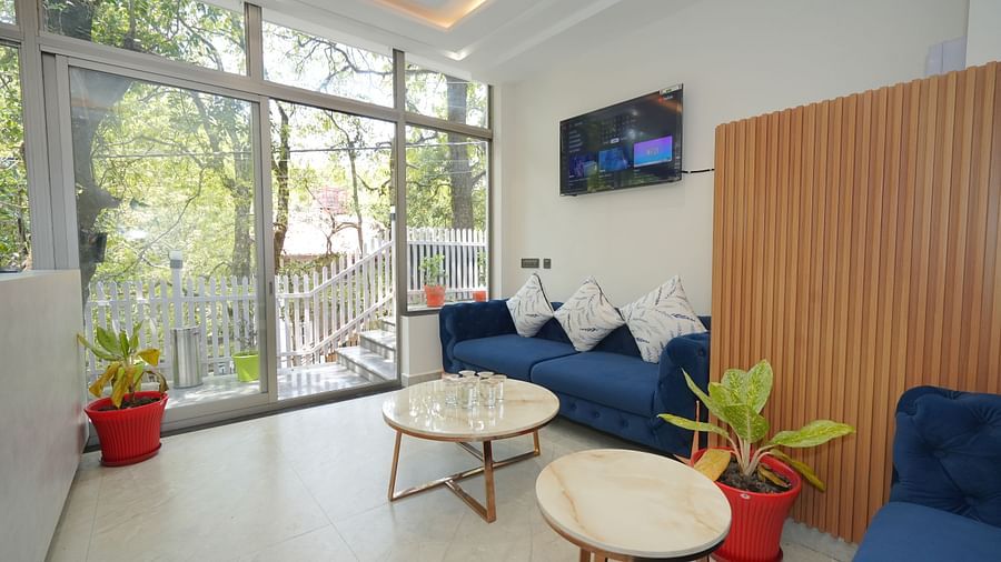 The waiting area near the reception at DLS The Emerald, Nainital with sofa set, tables, and the glass door leading outdoors