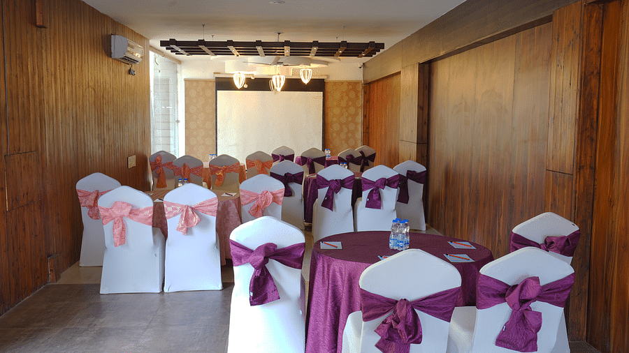 A shot of the Whispering Wind Hall at DLS Whispering Winds with chairs and tables facing the podium