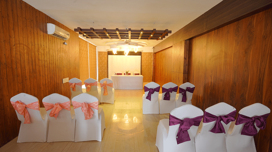 An image of the Whispering Wind Hall at DLS Whispering Winds with chairs, air-conditioning, and bright yellow lighting