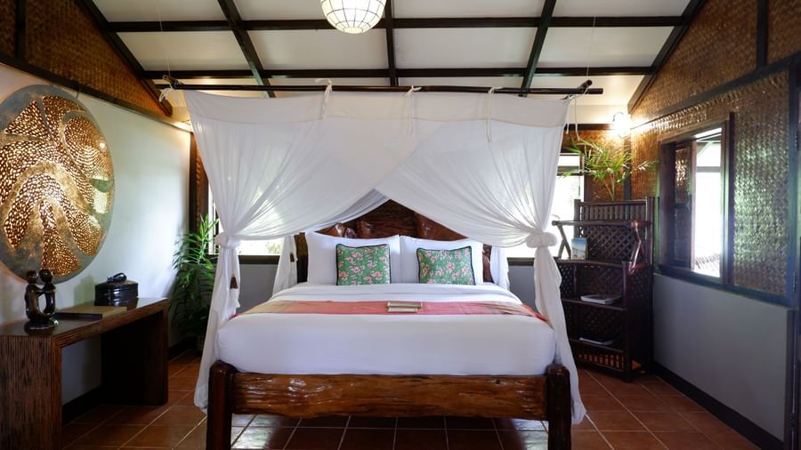 Cosy bamboo room with a queen canopy bed and wooden interiors at Flower Island Resort.