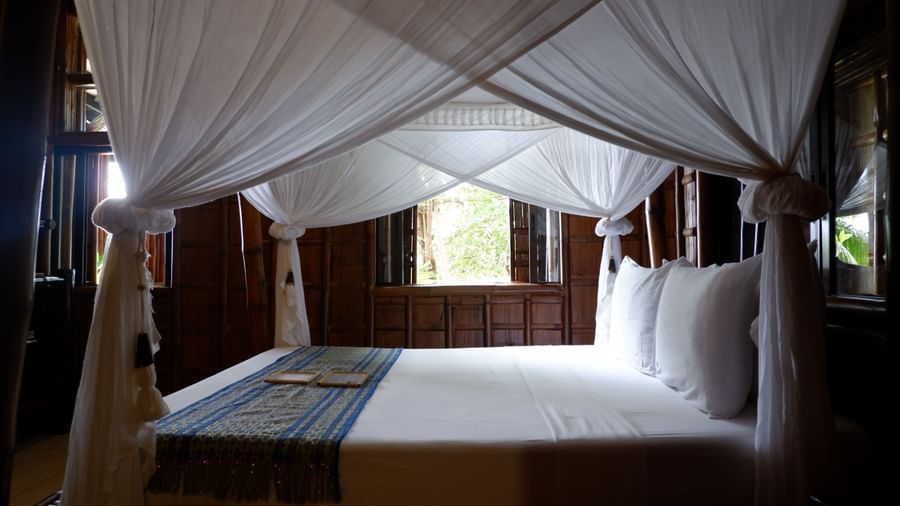 Spacious bedroom with canopy bed and garden views at Flower Island Resort.