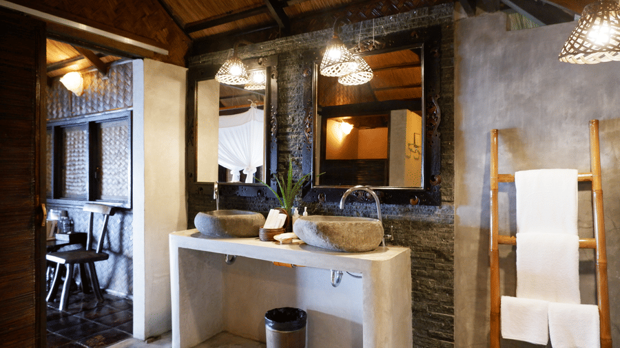 A bathroom space with two stoned sinks, mirrors, lights and toilteries at Flower Island Resort.