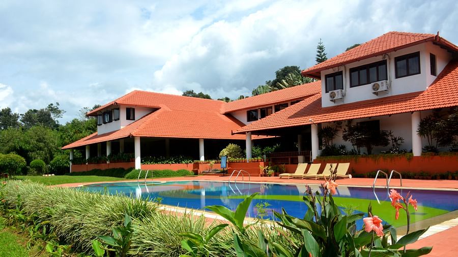 a view of the property with the swimming pool visible and a garden with bushes - Kadkani River Resort, Coorg