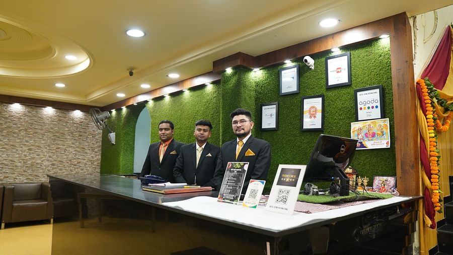An image of a reception desk with three receptionists standing behind the desk - Motel Divine International, Roorkee