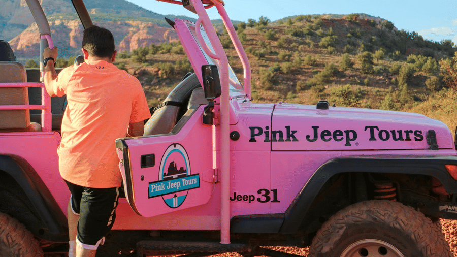 A person getting into a pink jeep with a mountain in the background - The Cindrella Hotel, Siliguri