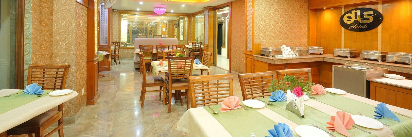 Dining area with a table and chairs, featuring the DLS logo on the wall and yellow ceiling lights illuminating the space at DLS Hotels The Rock Castle.